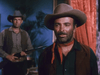 Two men in cowboy hats pose indoors—one in a red neckerchief and vest, the other holding a rifle—against a blue wall with a plant. This Western scene recalls classic films like "Outlaw Women (1952) DVD.