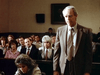 A man in a suit addresses the courtroom in A Deadly Silence (1989) DVD, evoking classic film scenes as he speaks to the judge or jury while others, including a woman in front, watch attentively from the gallery.