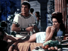 A man in ancient clothing holds a goblet beside a reclining woman enjoying fruit at a lavish banquet, evoking classic movie scenes—perfect for fans of rare finds like The Minotaur (1960) DVD.