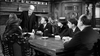 Five people in formal attire gather around a wooden table in an ornate room, as seen on the "Murder at the Gallop (1963) DVD," evoking a classic British mystery with wood paneling and decorative china.