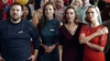 A group closely watches with surprised, concerned looks at a busy indoor event, as if reacting to a dramatic scene from the vintage classic "Hearts of Christmas (2016)" DVD.
