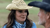 A woman in a straw cowboy hat and denim jacket chats with a man in a black cowboy hat outdoors, capturing the American West spirit featured in "The Real West (2024) DVD," set against a blurred green backdrop.