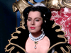 A woman in regal attire with black hair, pearls, and a jeweled crown sits on an ornate throne, capturing the elegance and rarity of classic films like The Adventures of Don Juan (1948) DVD.