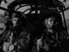 Two pilots in flight gear and oxygen masks sit in a military aircraft cockpit. This black-and-white scene from The Dam Busters (1955) DVD captures the classic World War II atmosphere of vintage British war films.