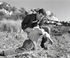 A man in Western attire kneels on rocky ground, holding another who has collapsed amid rugged hills and a fence—reminiscent of scenes from rare films like the Gun Duel at Durango (1957) DVD.