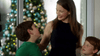 A woman smiles at two young boys, one in green and one in blue, by a decorated Christmas tree—ideal for fans of A Heavenly Christmas (2016) DVD or those seeking a rare Christmas angel film on DVD.