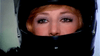 Close-up of a light-eyed, blonde-haired person wearing a black motorcycle helmet, evoking Monica Vitti in "Blonde in Black Leather (1975)" on DVD, with just their face visible through the helmet’s opening.