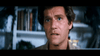 A man with short brown hair and blue eyes gazes upward with concern, resembling Robert Redford in a tense scene from "The Hot Rock (1972)" DVD. He is indoors, with blurry bookshelves visible in the background.