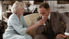 An older woman in a light blue robe comforts a man in a suit on a couch in an elegant, softly lit 1923 London living room, evoking a tender scene from the film "Mrs. Dalloway (1997)" available on DVD.