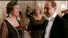 A smiling woman in a black embellished dress and headpiece stands beside a man in a tuxedo, with another woman in green behind them—reflecting the 1923 London elegance of the "Mrs. Dalloway (1997) DVD.