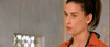 A woman with dark hair tied back, in an orange shirt over a dark top, stands indoors by a barred window with a serious look—evoking the psychological romantic thriller style of the "Passion of the Mind (2000) DVD.