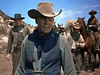 A group of cowboys in western gear stands under a blue sky with horses, evoking classic films—scene from Carson City (1952) DVD.