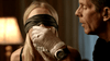 In a tense, dimly lit scene reminiscent of rare films on DVD, a gloved person assists a blindfolded woman in drinking—evoking the suspenseful atmosphere found in "An Officer and a Murderer (2012) DVD.