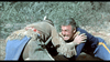 Two men in period costumes grapple on the ground outdoors; one wears fringed brown attire and a feather headband, while the other is a tense 7th Cavalry soldier—reminiscent of scenes from the 7th Calvary (1956) DVD. Bushes appear in the background.