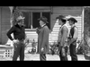 Four men in cowboy hats stand outside a wooden building, talking. The black-and-white scene evokes the Old West—reminiscent of a moment from the Gunfighters of Abilene (1960) DVD.