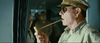 A man in uniform and sunglasses, with a pipe in his mouth, evokes classic WWII imagery on the "Emperor (2012) DVD," with blurred soldiers in the background.