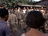 A group of armed soldiers in uniform confronts civilians outside rural buildings in daylight—a tense scene reminiscent of vintage classics or a World War II film like Ambush Bay (1966) DVD.