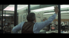 A man in a dress shirt and vest stands with his back to the camera, reaching for a glass office wall as he looks into a bustling newsroom—an image reminiscent of scenes from Runaway (1984) DVD.
