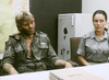 A disheveled man in a dirty uniform sits beside a woman in military attire at a table, with a map and safe behind them—a scene reminiscent of classic films like Warhead (1977), now available on DVD.