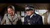 Two men in German military uniforms from "Tank Force (1958) DVD"—one in tan, the other in a black SS outfit with cap and goggles—stand indoors before clipboards and tan curtains, both looking down with serious expressions.