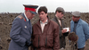 Four men stand in a sunflower field; one wears a gray military uniform speaking to a man in a brown jacket, while two others—one with a notepad—look on, evoking memorable scenes from the Citizen X (1995) DVD.