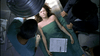 A woman lies on a metal table under a green sheet, seemingly unconscious, as a medical professional and two others stand nearby—a scene from the rare "Murder Most Likely (1999) DVD.