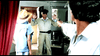 A man in a light outfit and sunglasses stands with his hands up as someone points a gun at him. Joan Collins, in a wide-brimmed hat, appears—just like a scene from The Cartier Affair (1984) DVD.
