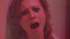 A distressed red-haired woman screams with teary eyes and an open mouth, bathed in pinkish-red light—evoking scenes from the cult classic Slumber Party Massacre II (1987) DVD.