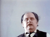 A middle-aged man with thinning hair and a startled look gazes upward, evoking a classic horror scene from "Don’t Look in the Basement (1973)" DVD. He wears a white shirt, dark vest, and tie against a plain light background.