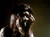 A distressed person with long, dark hair hides their face in their hands, set against a shadowy backdrop that evokes the chilling atmosphere of the "Don’t Look in the Basement (1973) DVD.