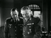 Two men in military uniforms with medals stand together indoors, looking down at something out of frame. This black and white scene is from the rare film "The Green Devils of Monte Cassino (1958)" on DVD, set in a military office.