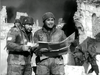Two soldiers in winter gear study a map amid ruins, recalling scenes from rare films like the German paratrooper movie "The Green Devils of Monte Cassino (1958) DVD," with black and white visuals evoking wartime devastation.