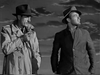 Two men in trench coats and hats stand outdoors under a cloudy sky, each looking away, evoking classic film intrigue in this black and white scene from the "Target Unknown (1951) DVD.