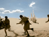 Three soldiers in desert uniforms rush across sandy terrain with explosions behind them, evoking classic scenes from the Sahara (1995) DVD as plumes of sand rise beneath a partly cloudy sky.