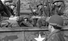 A group of helmeted soldiers sit in a military truck with a white star, recalling classic Korean War scenes. Hills rise in the background. From War Hunt (1962) DVD.