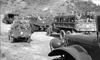 Black and white photo from War Hunt (1962) DVD shows military trucks and jeeps with soldiers in helmets on a dirt road, against a hilly backdrop, evoking classic vintage Korean War movie scenes.