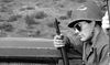 A soldier in helmet and sunglasses with a rifle leans on wood, recalling vintage classics; blurred outdoors behind him. War Hunt (1962) DVD.