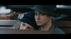 A young woman in a blue hat leans on a serious-looking young man’s shoulder as they sit close together with luggage behind them, evoking scenes from the true crime film "A Is For Acid (2002) DVD.
