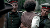 Two soldiers in green uniforms hold a person with curly hair, dressed in a brown vest and cream shirt, their faces serious against blurred greenery—a unique scene from Einstein and Eddington (2008) DVD for rare movie collectors.
