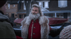 A man dressed as Santa in a red coat with fur trim stands outside with others in the snow—just like a scene from The Christmas Chronicles (2018) DVD.