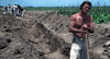 A shirtless man leans on a shovel in a dirt field, while others work nearby under a blue sky—a scene reminiscent of classic films like the White Lightning (1973) DVD.