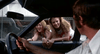 Two young women lean into a car's window, smiling and chatting with the driver—an image that echoes scenes from classic films like White Lightning (1973) DVD, with city streets and buildings visible in the background.