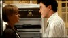 A woman and a man stand facing each other in front of an open fridge with a black-and-white face photo inside, having a serious conversation about the movie "Chances Are (1989)" DVD.