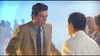 A man in a tan suit and striped tie appears surprised facing another man in a white jacket, with others blurred in the background—evoking a scene from Chances Are (1989) DVD starring Robert Downey Jr.