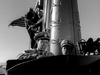 Two naval officers in uniform stand on a submarine’s deck, with an American flag and periscope behind them—a striking black and white scene recalling vintage films like Submarine Command (1951) DVD.