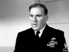 A man in a military uniform with medals and badges stands indoors against a plain background, gazing seriously to the side—evoking classic films like Submarine Command (1951) DVD.
