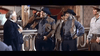 Four men in Western dress talk inside a vintage saloon, echoing classic Western cinema, as seen in "Three Graves for a Winchester (1966)" DVD—two in dark cowboy hats, one laughing, and an older man in a suit at the bar.