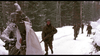 Four soldiers in winter gear walk through a snowy Ardennes forest, recalling scenes from World War II, as depicted in "A Midnight Clear (1992)" DVD. Two are foregrounded—one with a white cloth—while two follow behind, all carrying rifles among snow-covered trees.