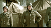 Three men in military uniforms stand before brown tents and wooden huts in a snowy forest, their tense expressions evoking the wartime drama of A Midnight Clear (1992) DVD.