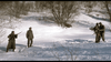 Three soldiers stand in a snowy Ardennes forest with bare trees, as seen in "A Midnight Clear (1992) DVD." Two are together on the right, one with a rifle, while another stands apart on the left. Snow blankets the ground and hills.